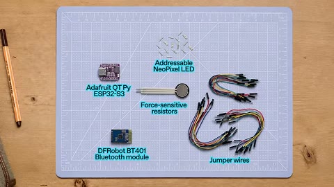 Source frame at 15.500s. Parts layout, coding laptop, toy with circuitry overlay.